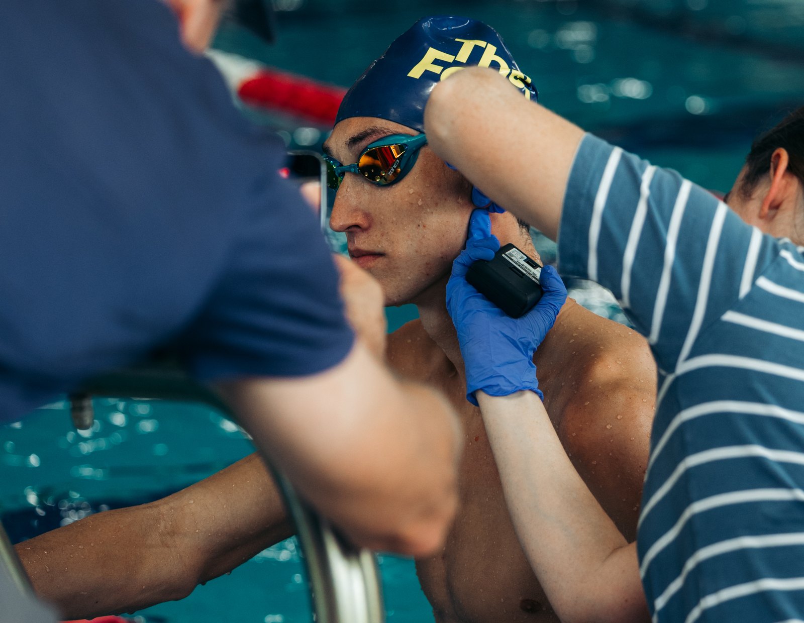 Capillary blood lactate being sampled at a swimmer’s ear at the pool wall during a swim test